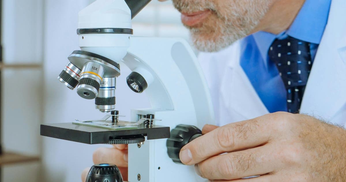 Medical professional examining a microscope slide in a laboratory.