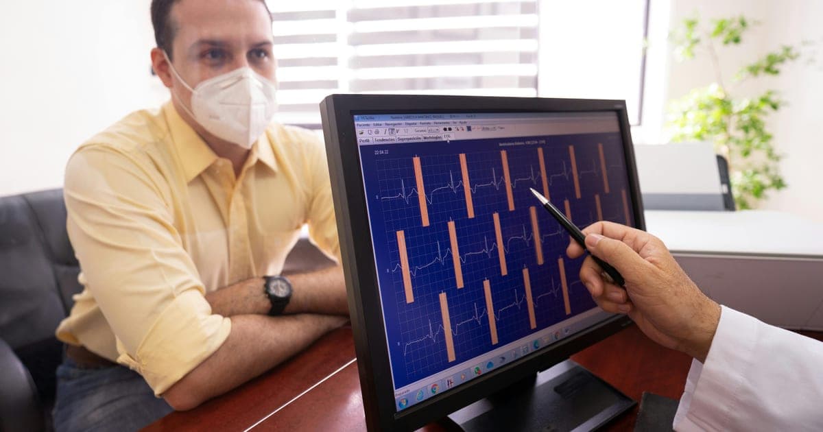 Doctor pointing to ECG results on a screen during a consultation.