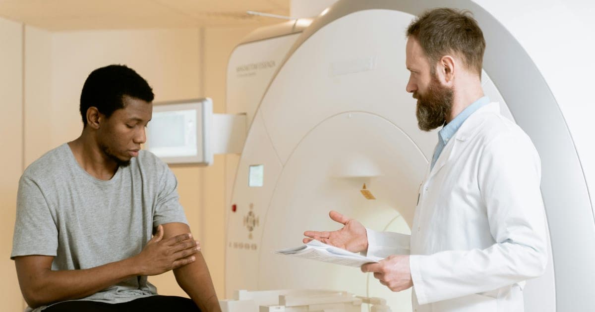Doctor consulting with a patient beside an MRI scanner.