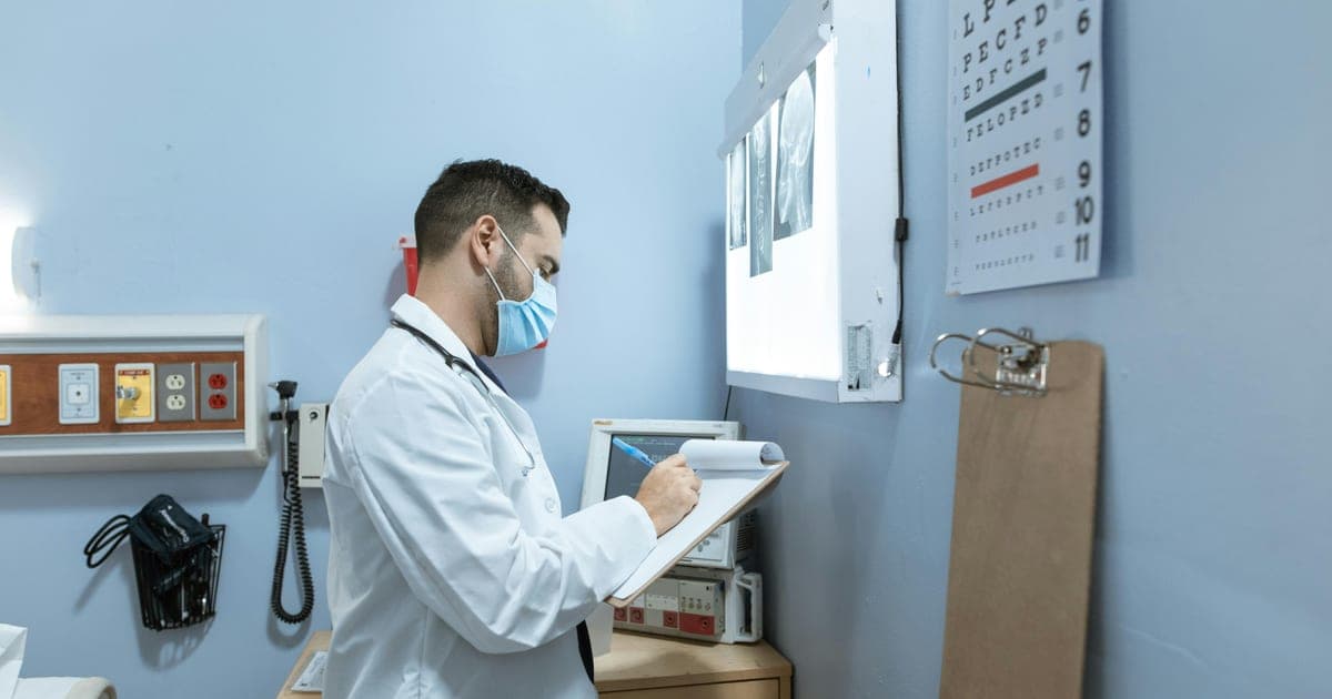 Doctor reviewing imaging results on a light board while taking notes.